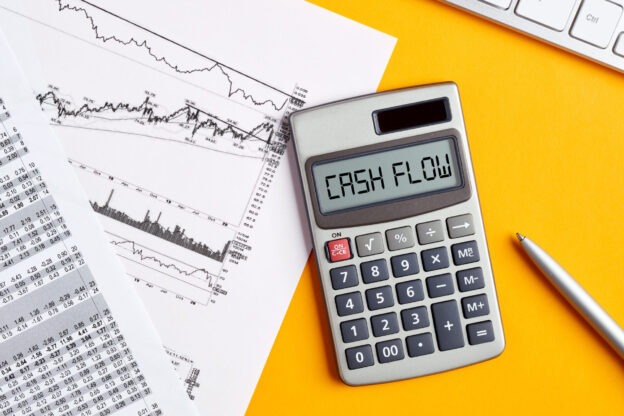 An image of a calculator that says cash flow laying on financial statements.