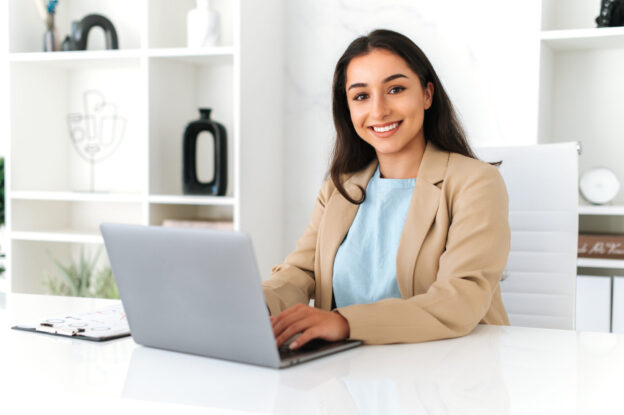 An image of a woman sitting at her computer doing payroll for a temp agency working on staffing factoring invoices.